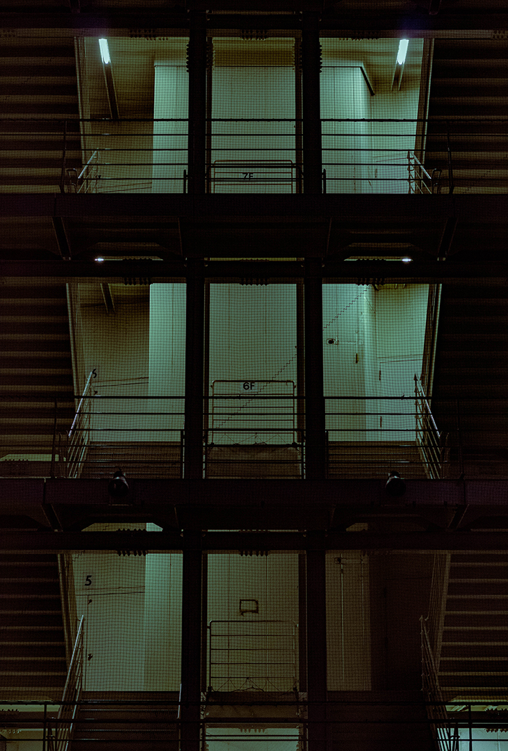 Flat framing of a dimly lit staircase with a net grid in front of it.